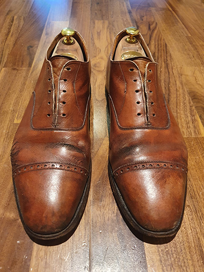 Pair of cracked, brown mens shoes with no laces